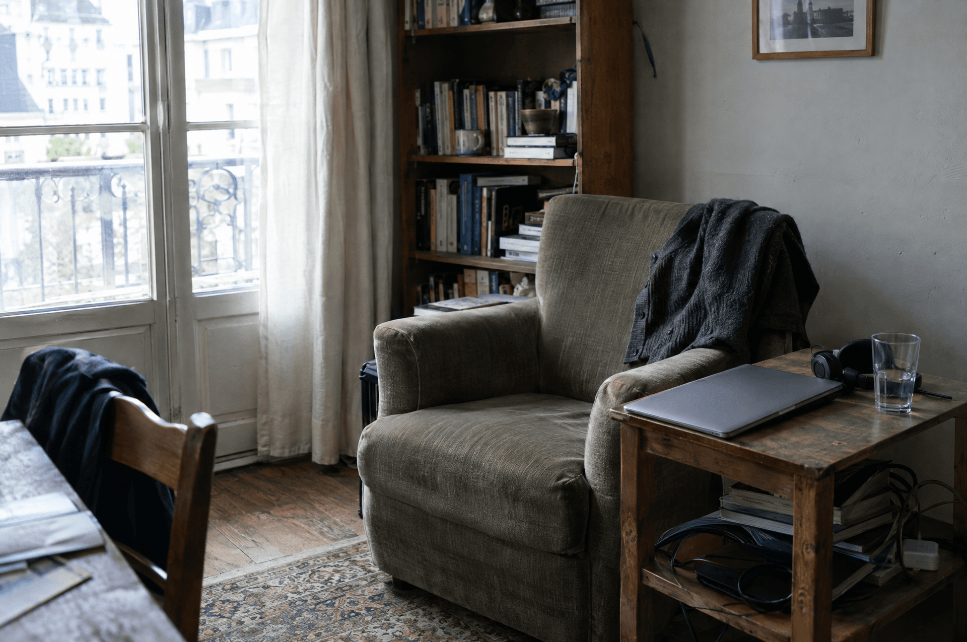 Un fauteuil chez soi avec un gilet plié, un ordinateur fermé et un casque.