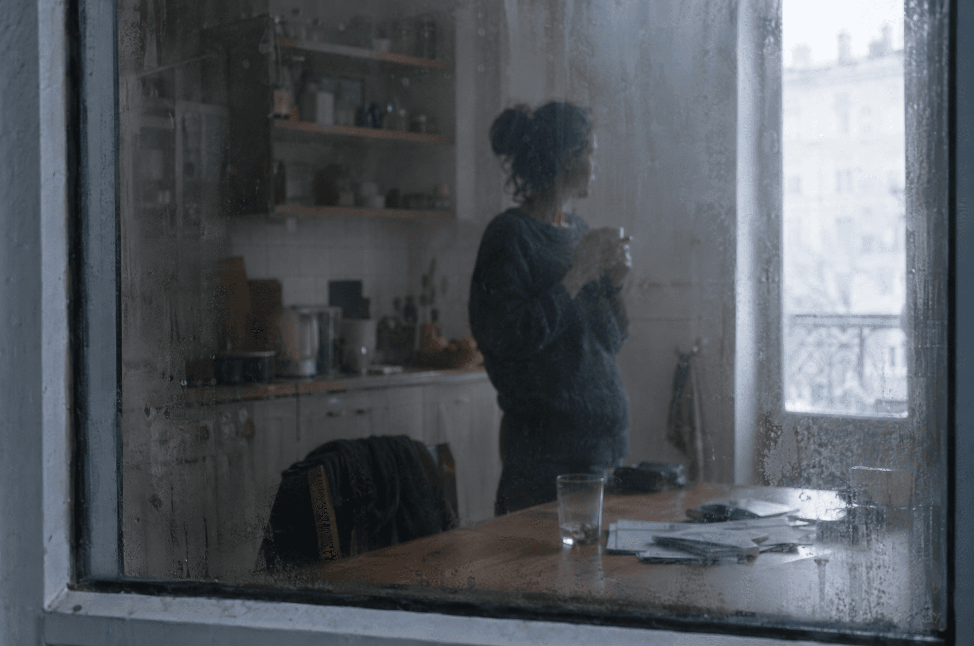 Une silhouette floue derrière une vitre couverte de buée.