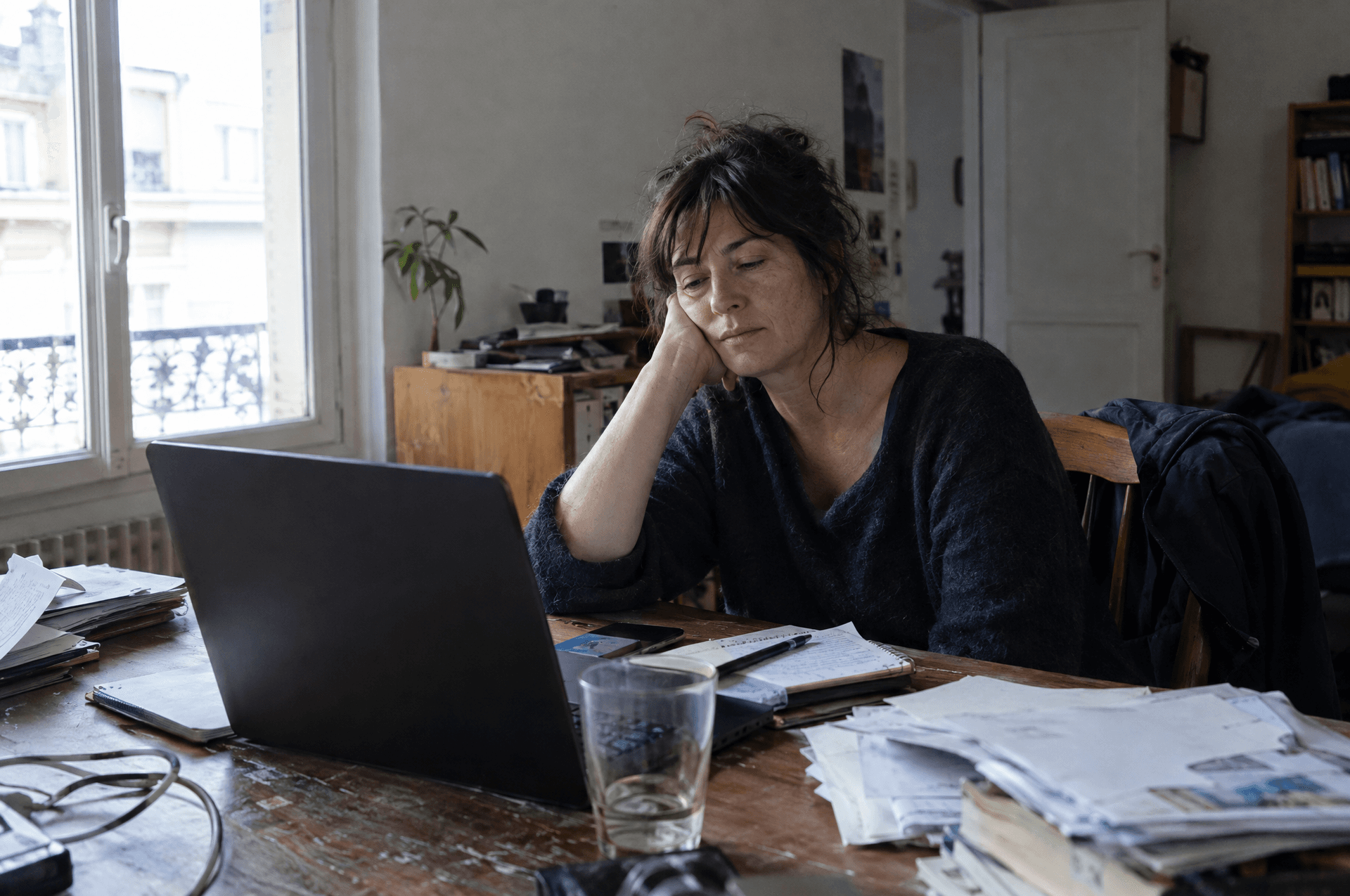 Une femme fatiguée à son bureau, la tempe appuyée sur la main.
