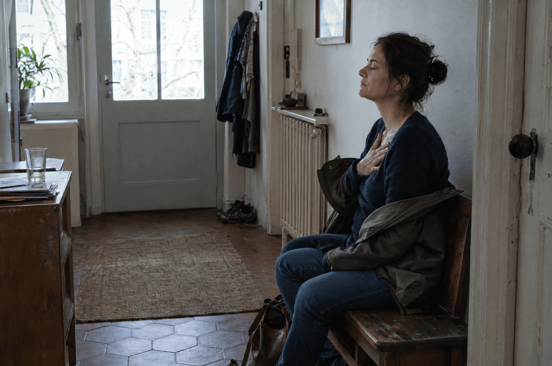 Une femme assise, une main posée sur la poitrine, les yeux fermés.